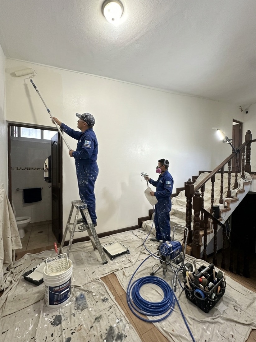 Equipo uniformado de Los Pintas pintando con equipo airless y protección total en una casa de la capital