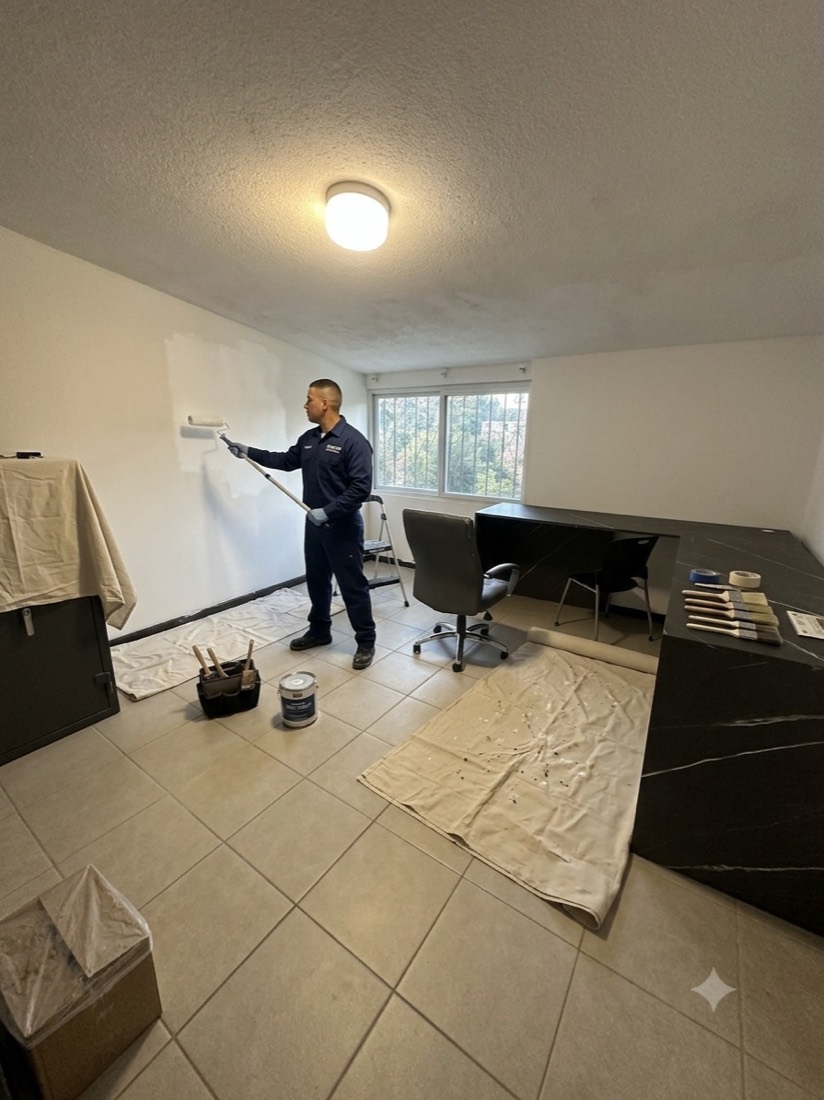 Pintor de Los Pintas pintando una oficina con muebles protegidos
