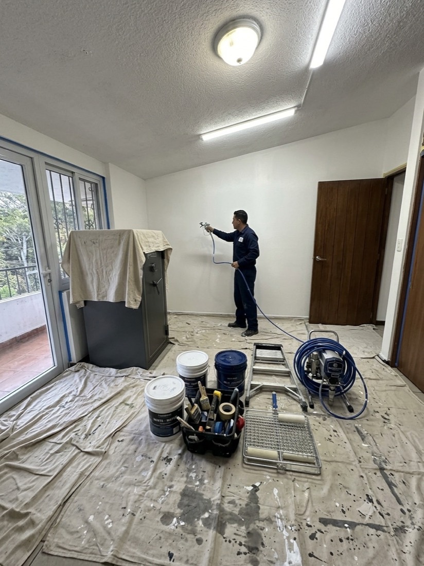 Pintor de Los Pintas aplicando pintura con equipo airless, muebles cubiertos
